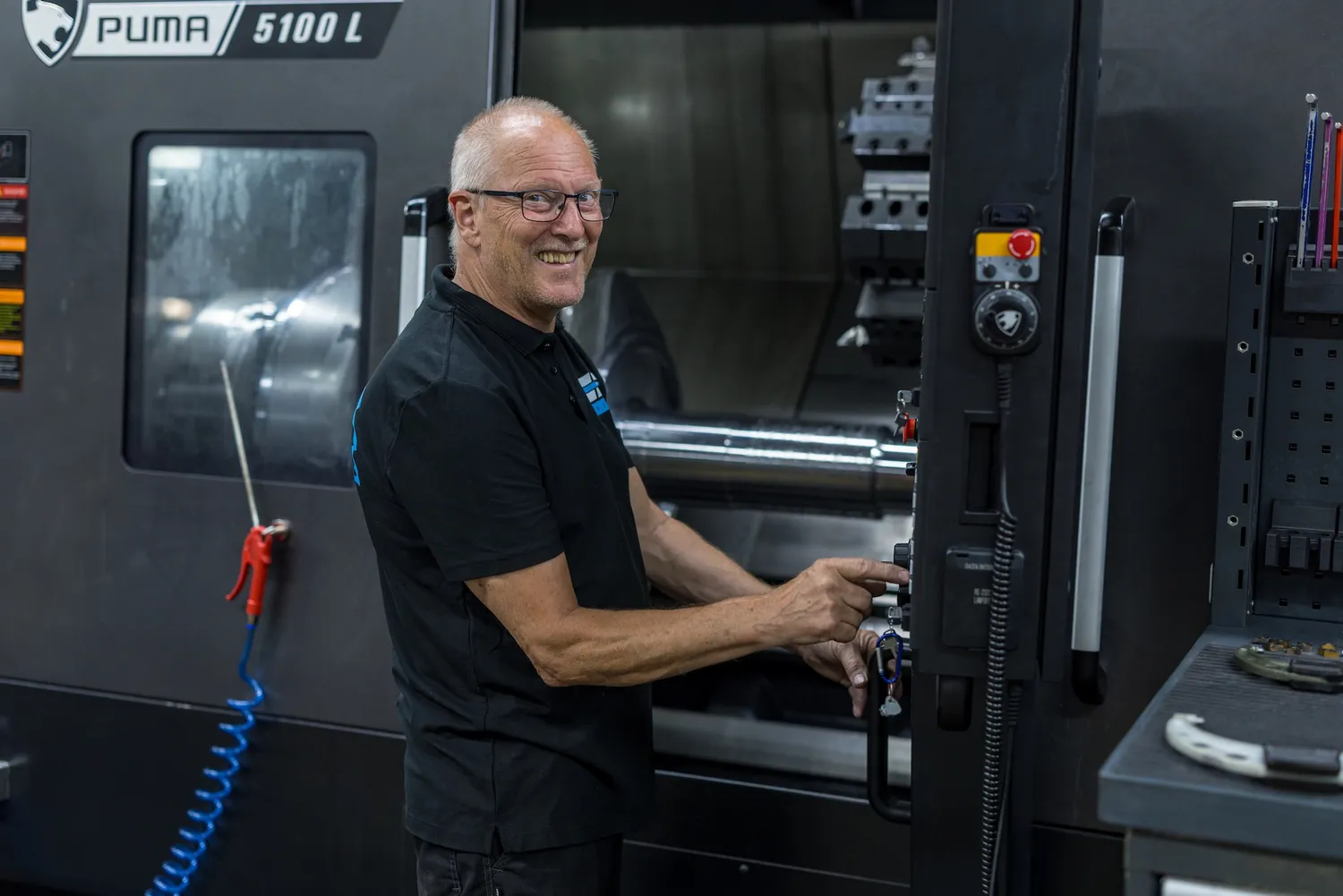 Lachende medewerker bedient een CNC draaibank