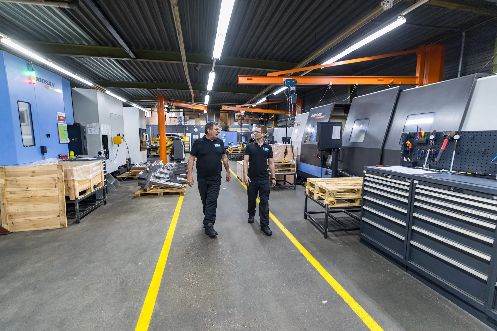 Collega’s in de werkplaats Twee collega's lopen door de werkplaats van CDF Techniek