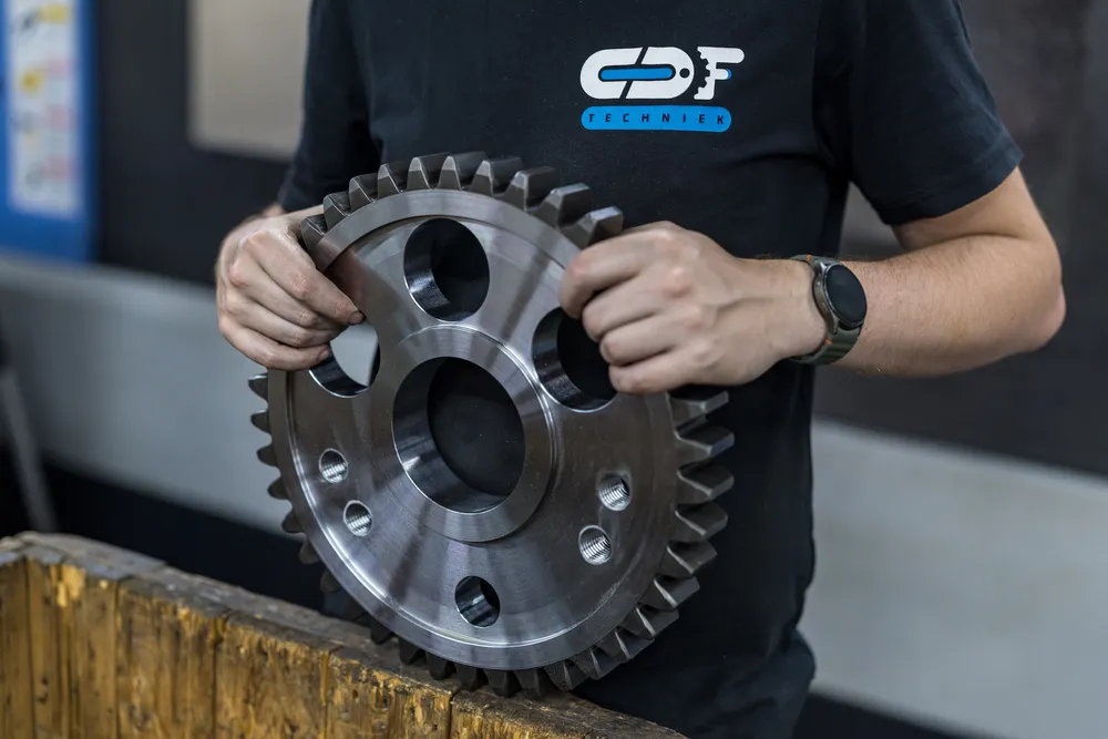 Gefreesd tandwiel Medewerker van CDF Techniek houdt een gefreesd tandwiel vast
