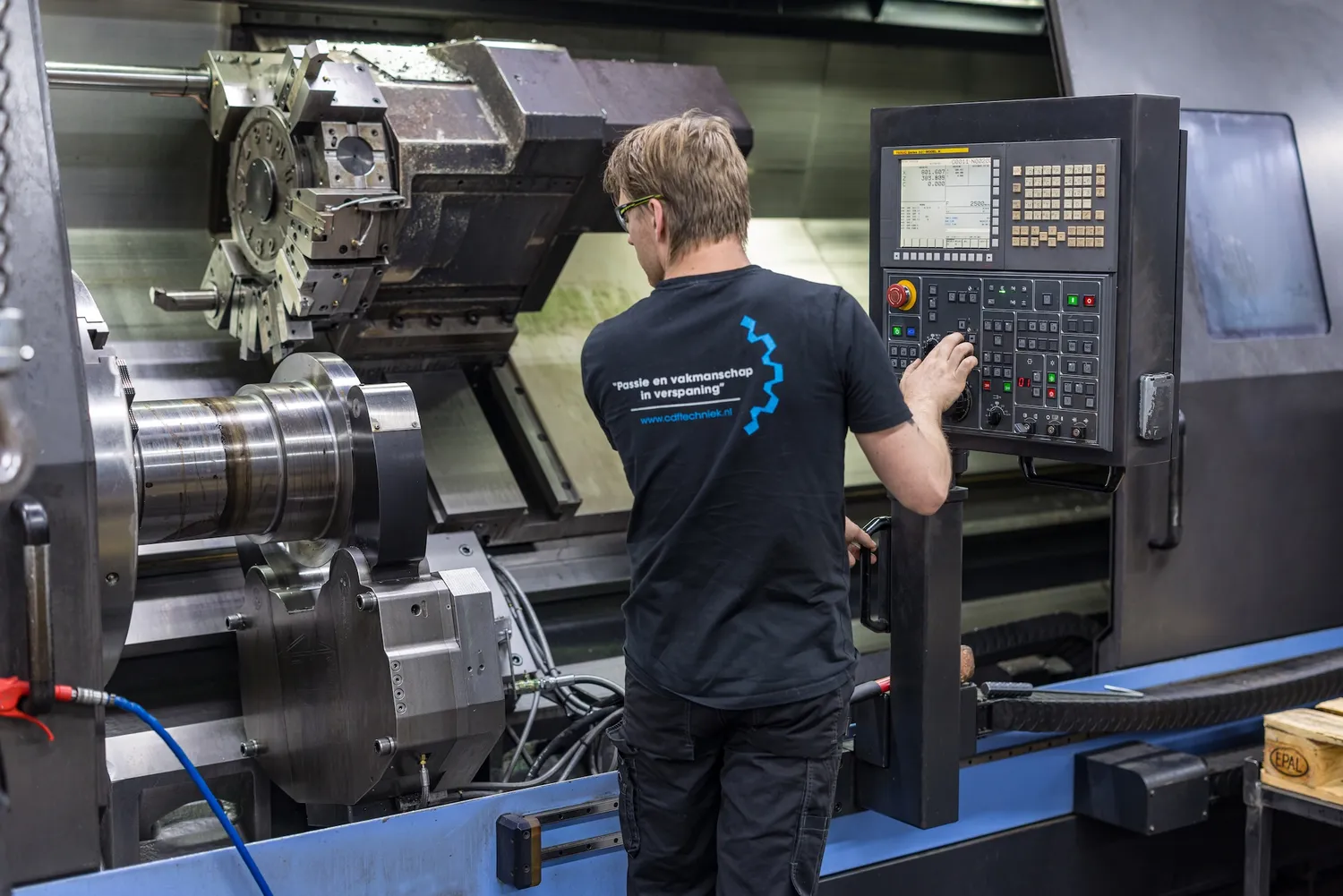 Medewerker bedient een grote CNC draaibank