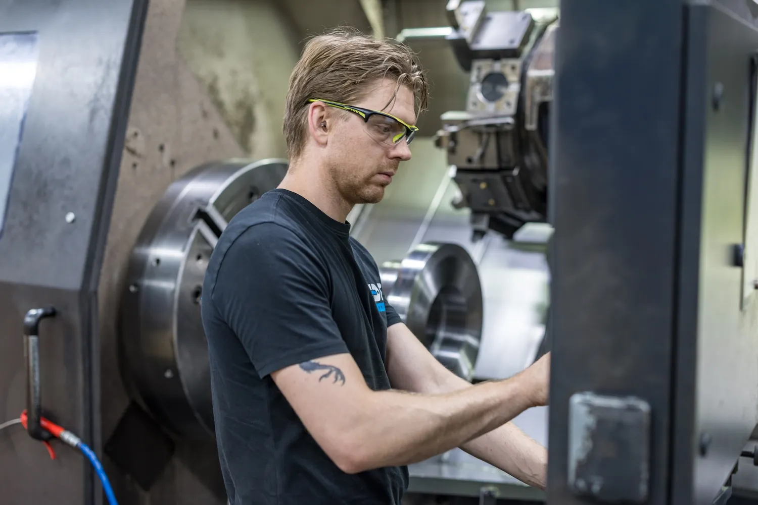CNC draaier aan het werk Medewerker met veiligheidsbril werkt aan een CNC draaibank