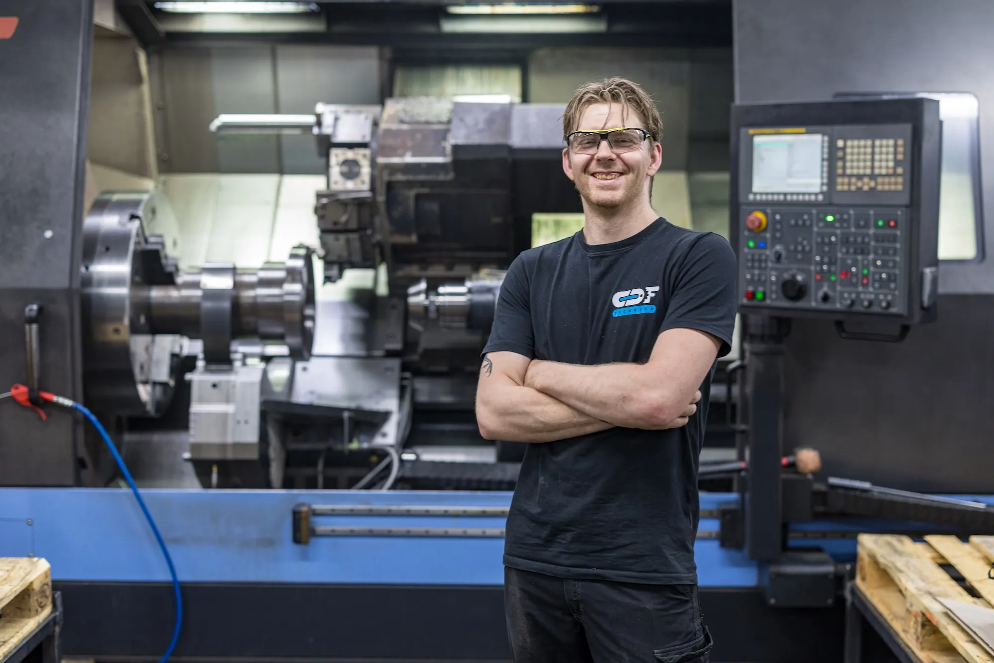 Vakman bij CNC draaibank Lachende medewerker van CDF Techniek voor een grote CNC draaibank